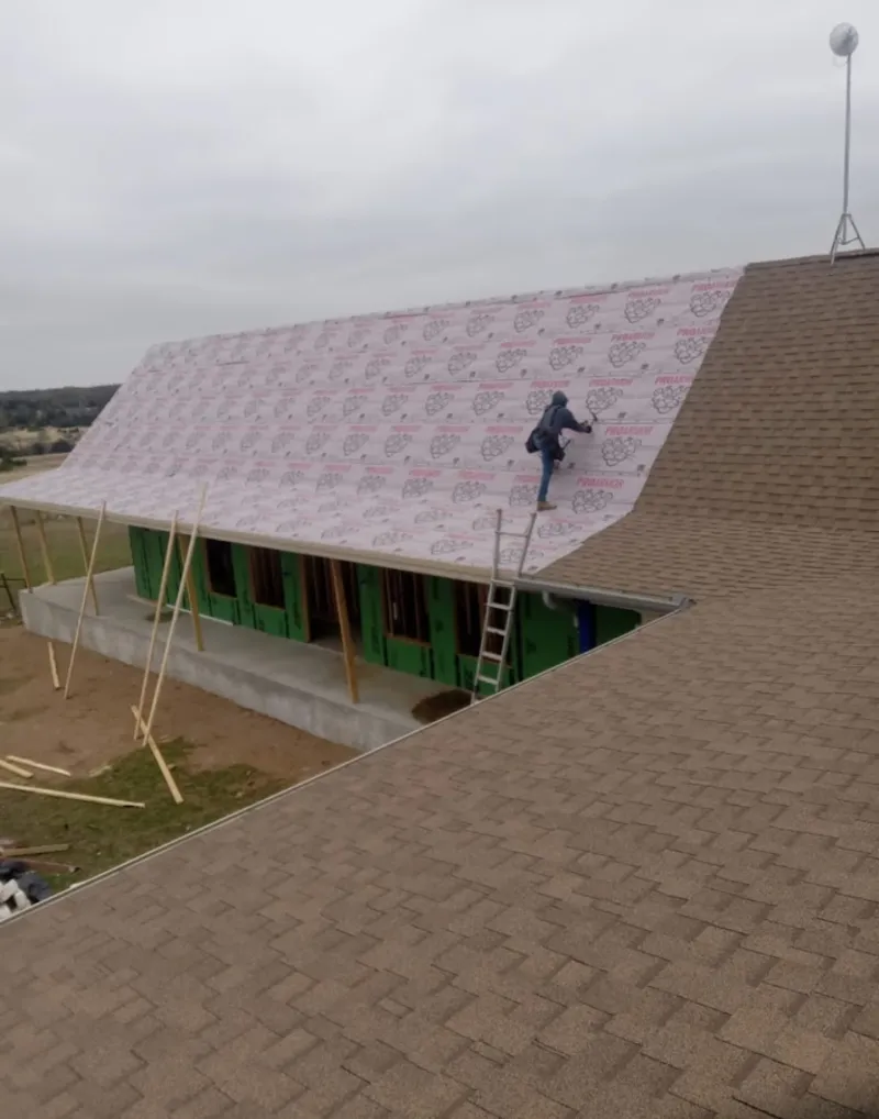 Worker preparing underlayment for a metal roof installation in Clear Lake